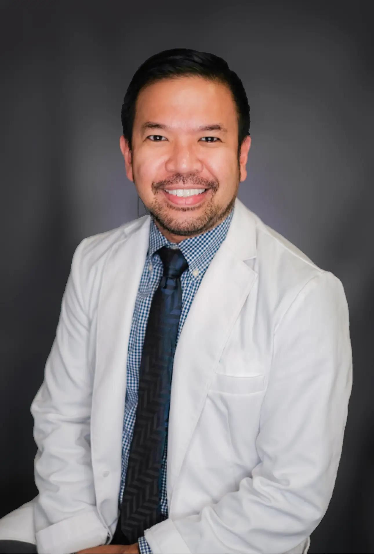 Richmond Ramirez, MD, in a white coat, photographed against a grey studio backdrop